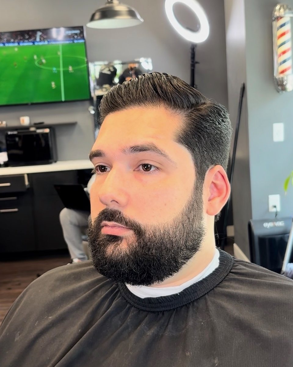 Slicked side part with a full, shaped beard